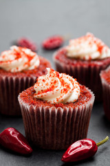 Chocolate  cupcakes with red hot chili pepper on black stone background