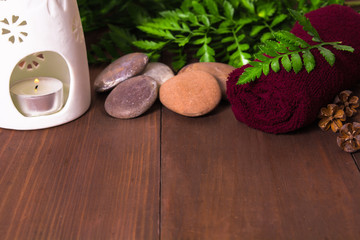 Fresh green fern, candle in aroma lamp, stones and towel for spa
