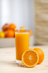 Orange juice in a tall glass with an orange half And basket of fruit in the background