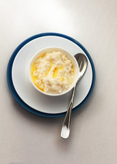 Porridge with milk and butter in a white plate with a blue frame