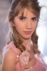 Girl in a gently pink dress in an interior studio