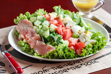 cobb salad - traditional american food,  hearty meal of salmon, eggs, cucumber, avocado and lettuce leaves with mustard dressing