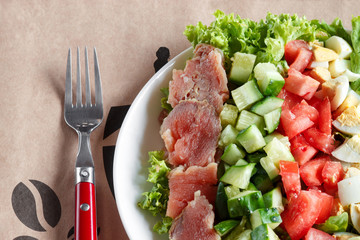 cobb salad - traditional american food,  hearty meal of salmon, eggs, cucumber, avocado and lettuce leaves with mustard dressing, top view