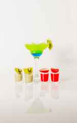 Colorful drink in a margarita glass, blue and green combination, many drinks in a shotglass