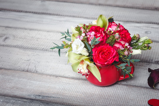 Bouquet of red roses in vase, hearts, callas on table, space for text