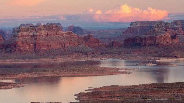 Time lapse of cliffs lit up at sunset over lake in the Utah desert
