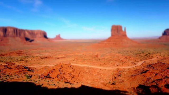 Tilt shift time lapse of cars driving a dirt road in Monument Valley