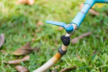 Garden hose or white rubber tube with faucet on grass field.