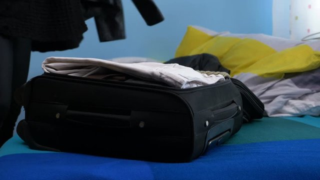 Woman trying to fit all the clothes in her small overfilled travel luggage