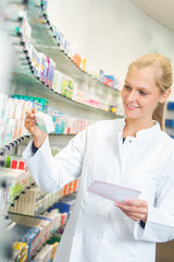 Junge Apothekerin sucht Medikamente aus einem Regal