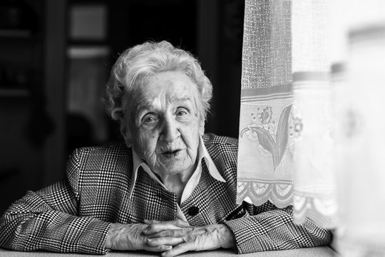 Strict elderly woman black and white portrait in the house.