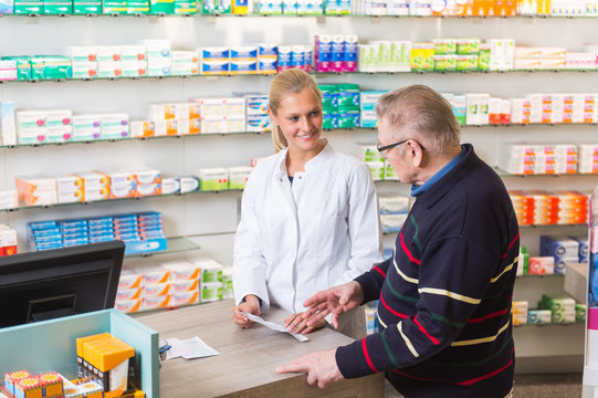 Junge Apothekerin bedient einen &auml;lteren Kunden