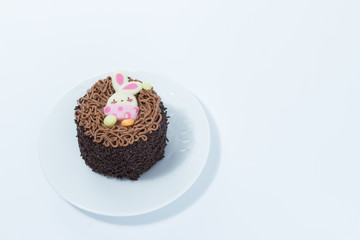 Small chocolate cake with Easter bunny detail on a white dish isolated in white background