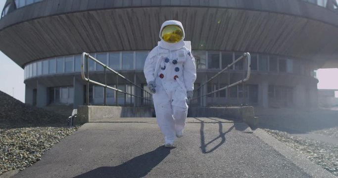 Funny astronaut doing a dance as he walks away from mission control building