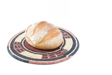 Crusty loaf of bread on a bamboo straw rustic placemat isolated on white background