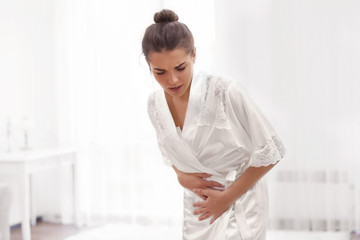 Young woman suffering from abdominal pain at home. Gynecology concept