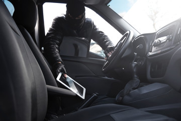 Thief stealing tablet from car