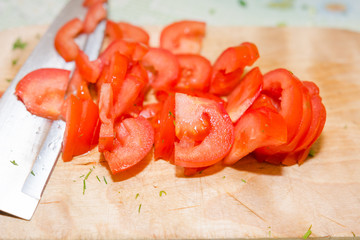 To cut a tomato. To cut tomatoes on a wooden board. Tamata for salad.
