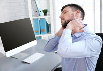 Posture concept. Man suffering from neck pain while working with computer at office