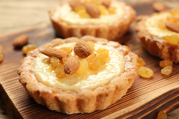 Delicious crispy tarts with almond and raisins on wooden board, closeup
