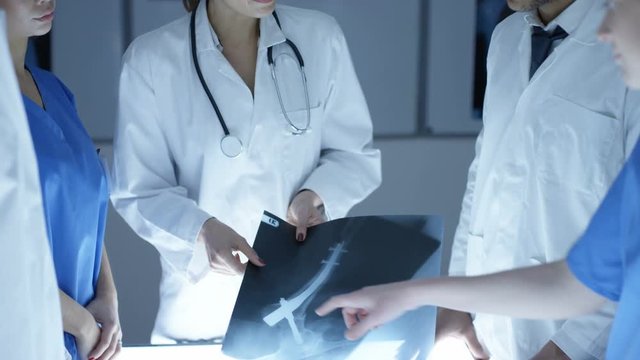  Medical team in a meeting, looking at patient x-rays on a light box