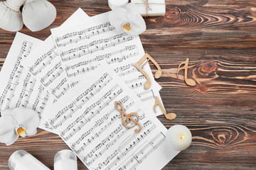 Fototapeta na wymiar Composition of music sheets and spa supplies on wooden background
