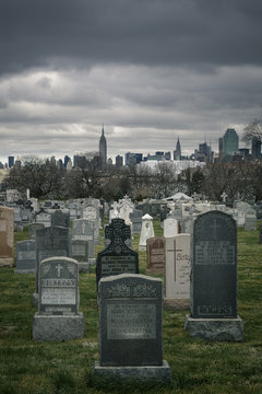 Calvary cemetery gravestones on a dark cloudy day with Manhattan skyscrapers in the background