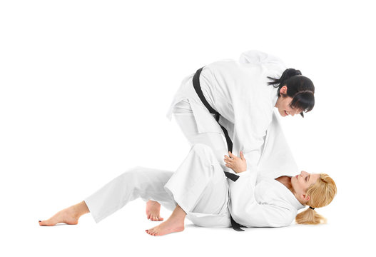 Young sporty women practicing martial arts on white background