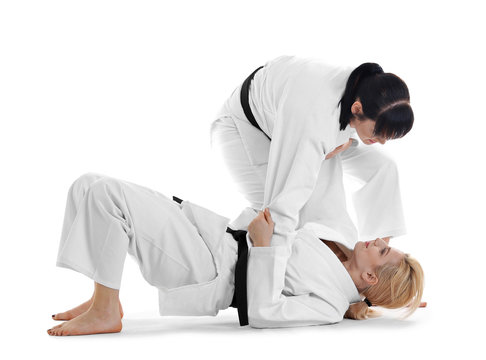 Young sporty women practicing martial arts on white background