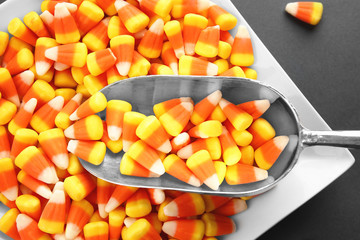 Plate with tasty Halloween candies and scoop on color background, closeup