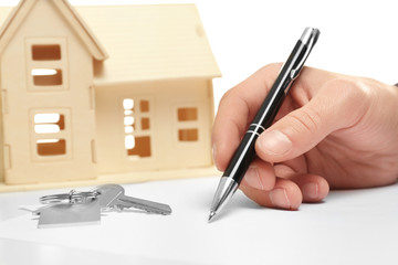 Male hand with pen and house model on table