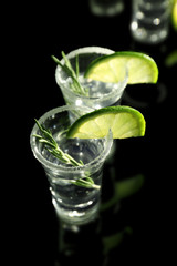 Tequila shots with juicy lime slices and salt on black background