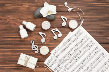 Fototapeta na wymiar Beautiful composition of spa accessories and musical notes on brown wooden background