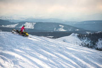 Fototapeta na wymiar Rider on the snowmobile in the mountains