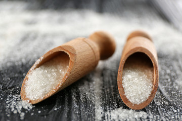 Decorative scoops with white sugar on black wooden background