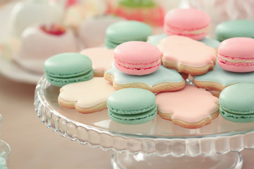 Glass stand with tasty macarons and cookies prepared for party, closeup