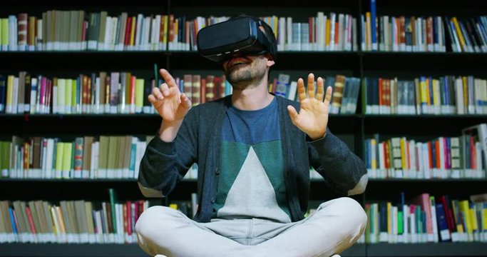 A beautiful young man in a library travels in a virtual futuristic world with augmented reality. Concept: educational, future, library, and immersive technology.