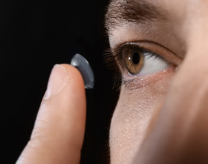 Young man putting contact lens, closeup