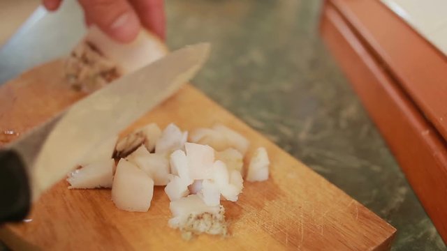 Cutting pork fat with a knife on a cutting board