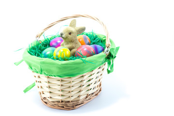 Fototapeta na wymiar Basket filled with green cloth and fake grass with Easter Bunny and six hand painted chicken eggs