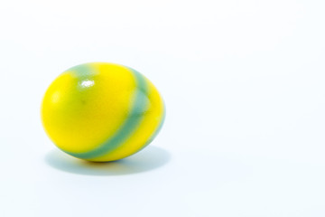 Easter egg hand painted in home - yellow with green stripes, isolated in white background