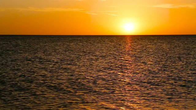 The setting sun cast a colorful orange glow over the Gulf of Mexico on a calm and clear evening in this looping video.