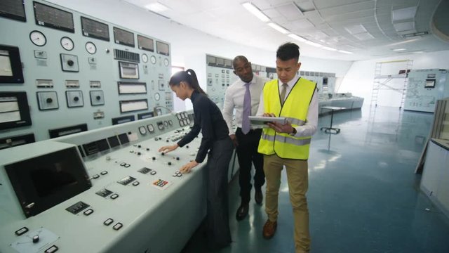  Mixed ethnicity team of engineers working in power station control room