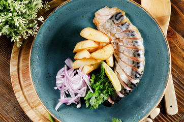 Smoked mackerel with potato slices, onions and greens