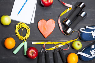 Heart, fruit and dumbbells. Fitness, healthy lifestyle on a black wooden background