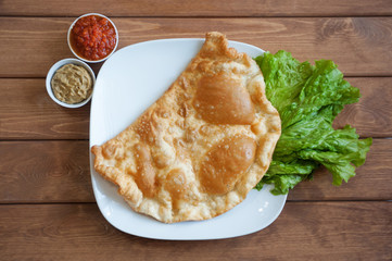Cheburek - meat pasty on the white plate. Top view.