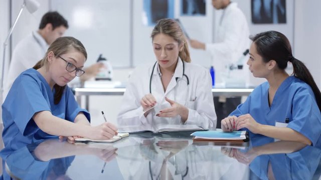  Female medical team in a meeting with male colleagues working in background