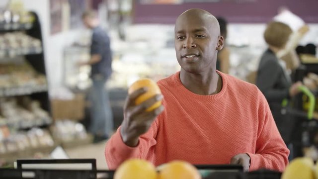  Cheerful African american man buying fresh fruit in the supermarket