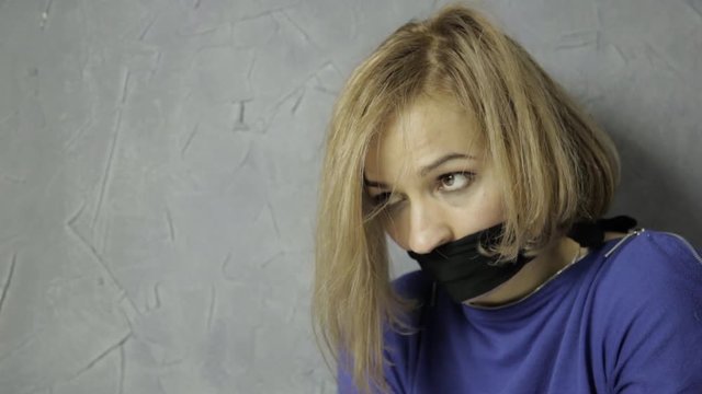 frightened girl gagged sits on the floor. kidnapping and violence