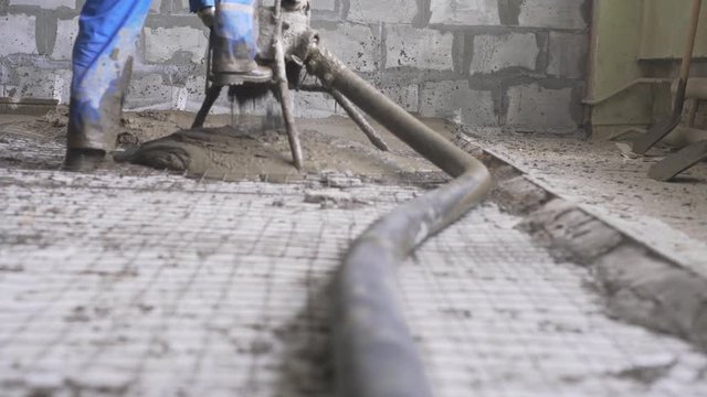 Worker making cement screed on the floor view